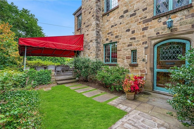 doorway to property featuring a yard, stone siding, and a wooden deck