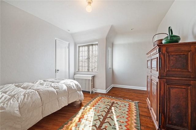 bedroom with baseboards, radiator heating unit, dark wood-type flooring, and vaulted ceiling