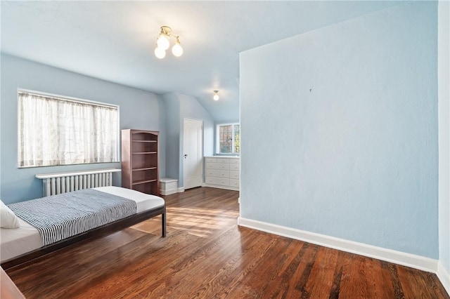 bedroom featuring baseboards, wood finished floors, and vaulted ceiling