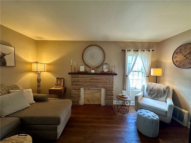 living room featuring a fireplace, wood finished floors, visible vents, and baseboards