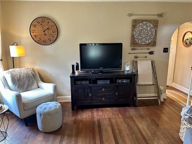 living room featuring arched walkways, baseboards, and hardwood / wood-style floors