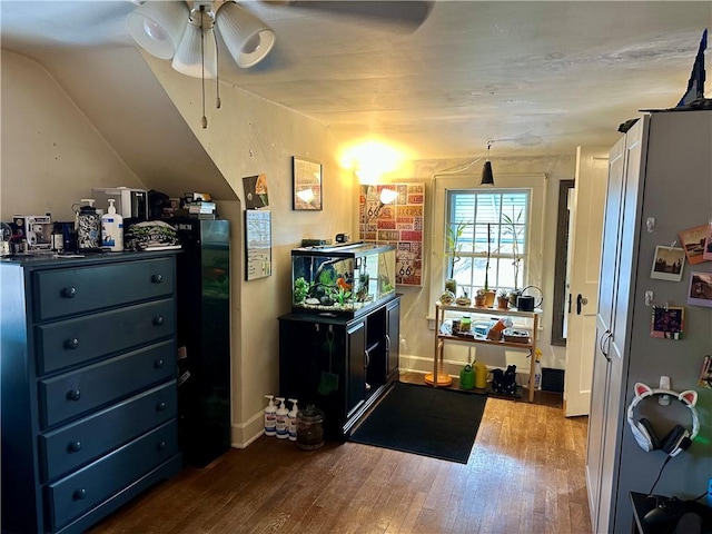 interior space featuring hardwood / wood-style floors, lofted ceiling, a ceiling fan, and baseboards