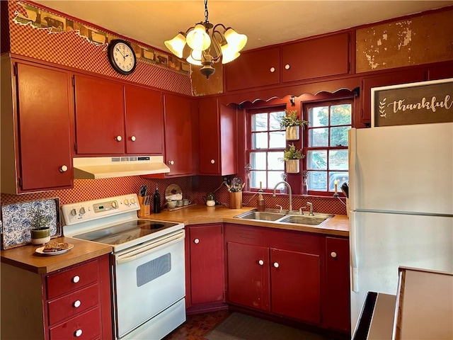 kitchen with white appliances, a sink, under cabinet range hood, tasteful backsplash, and red cabinets