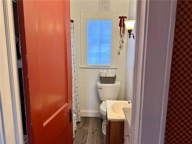 bathroom with visible vents, baseboards, toilet, wood finished floors, and vanity