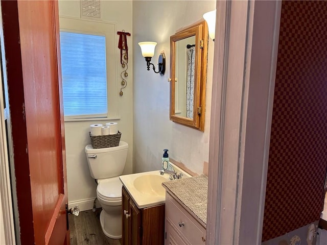 bathroom featuring visible vents, baseboards, toilet, wood finished floors, and vanity