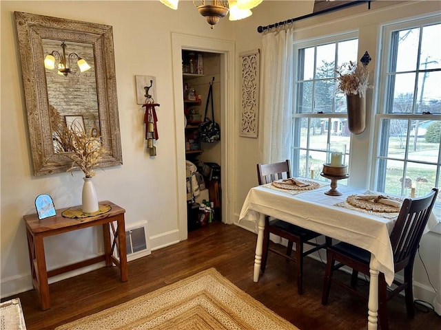 dining area with dark wood finished floors, visible vents, baseboards, and an inviting chandelier