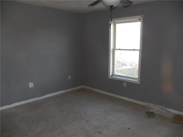 carpeted spare room featuring a ceiling fan and baseboards