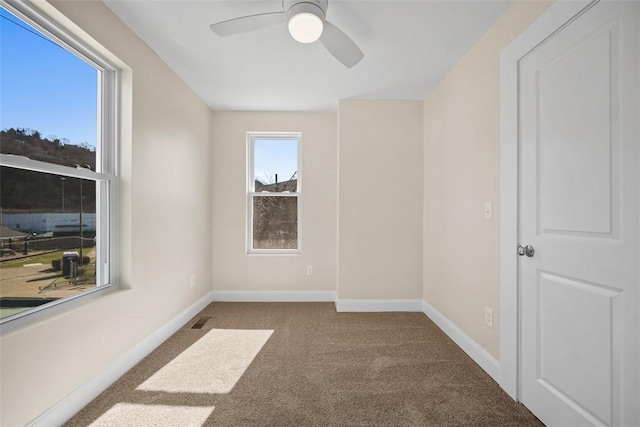 spare room featuring visible vents, carpet, baseboards, and ceiling fan