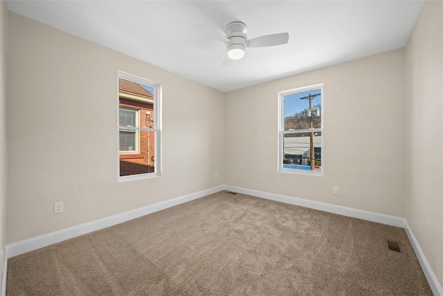 carpeted empty room featuring visible vents, baseboards, and ceiling fan