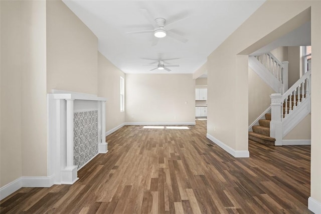 unfurnished living room with stairway, wood finished floors, baseboards, and ceiling fan