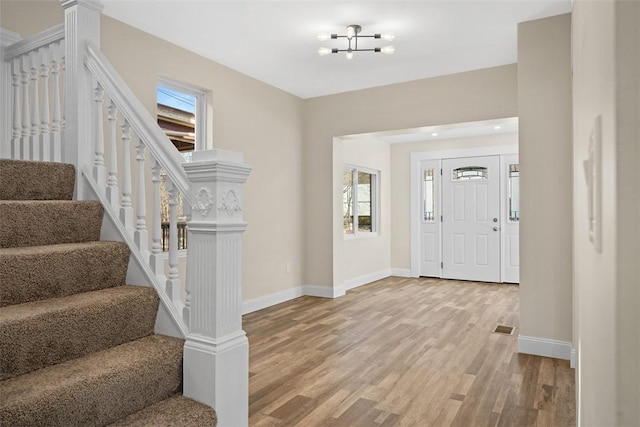 foyer featuring light wood-type flooring, baseboards, visible vents, and stairs