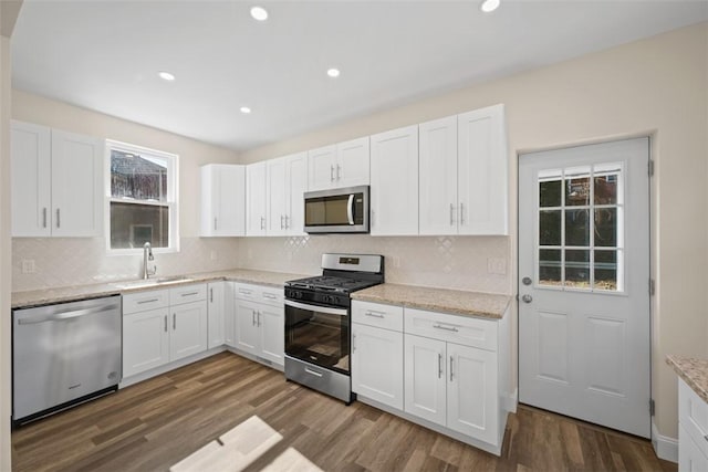 kitchen with a sink, stainless steel appliances, dark wood-style floors, and white cabinetry