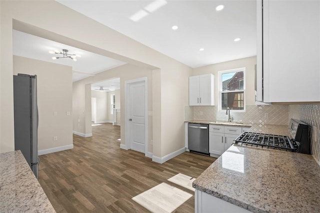 kitchen featuring backsplash, light stone countertops, dishwasher, gas range oven, and freestanding refrigerator