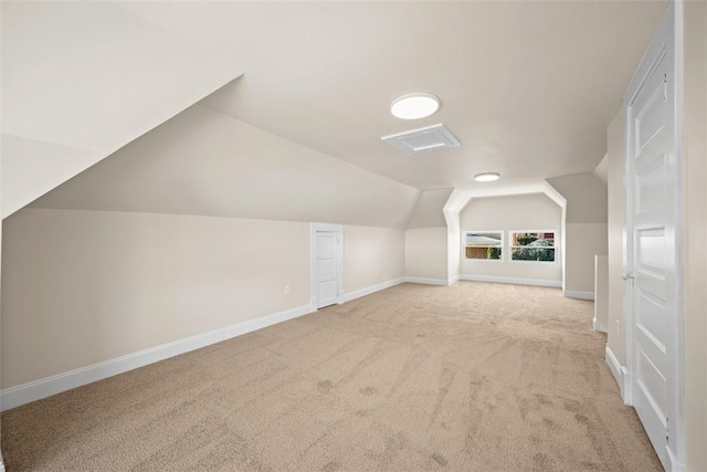 additional living space with baseboards, light colored carpet, and lofted ceiling