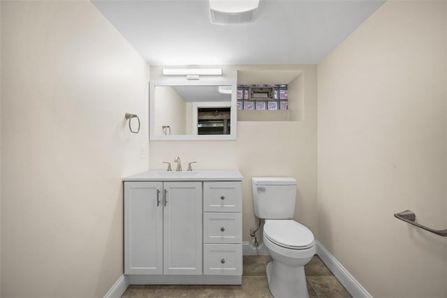 half bathroom featuring baseboards, toilet, and vanity