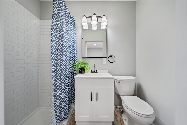 bathroom featuring a tile shower, toilet, and vanity