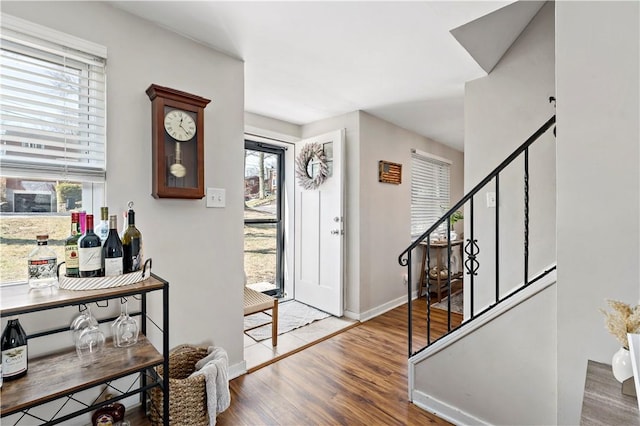 foyer featuring a bar, stairs, baseboards, and wood finished floors