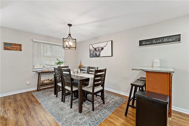 dining space with an inviting chandelier, baseboards, and wood finished floors