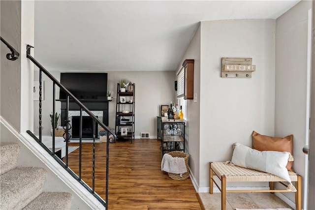 interior space featuring a fireplace, wood finished floors, visible vents, and baseboards