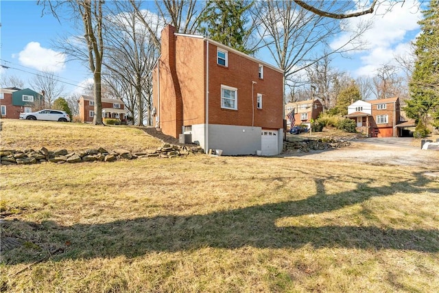 view of side of home with brick siding, a lawn, a chimney, and a garage