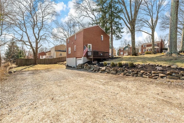 exterior space with fence, a residential view, a deck, a garage, and driveway