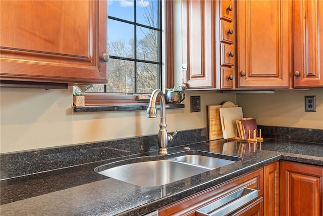 kitchen with brown cabinets, dark stone counters, and a sink