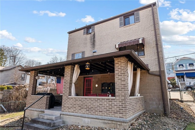 view of front of property with brick siding, a porch, and fence