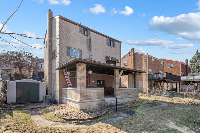 back of property featuring a porch, a shed, an outdoor structure, brick siding, and a chimney