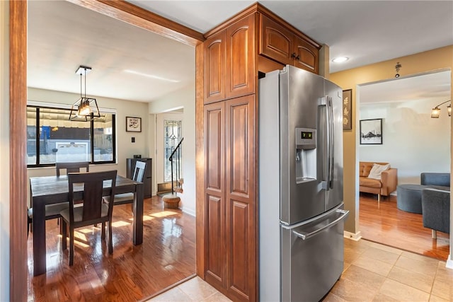 kitchen featuring light tile patterned flooring, brown cabinets, pendant lighting, and stainless steel fridge with ice dispenser