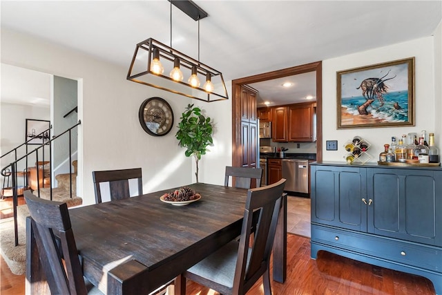 dining space with recessed lighting, wood finished floors, and stairs