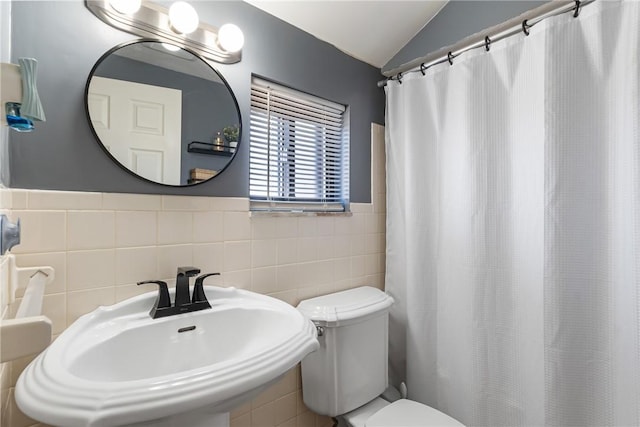 bathroom with a sink, curtained shower, toilet, and vaulted ceiling