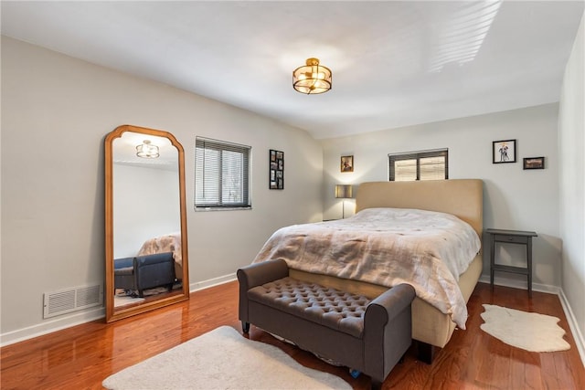 bedroom with visible vents, baseboards, multiple windows, and wood finished floors