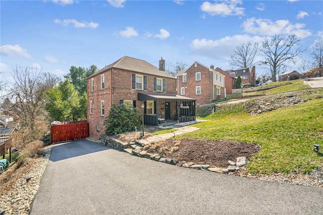 view of front of house with brick siding, a porch, and driveway