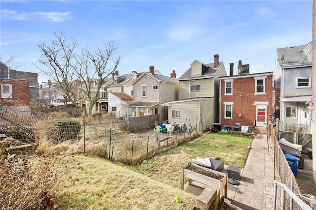 rear view of property featuring entry steps, a yard, fence, and a residential view