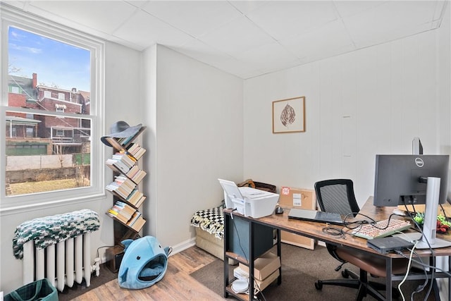 home office with radiator heating unit, baseboards, and wood finished floors