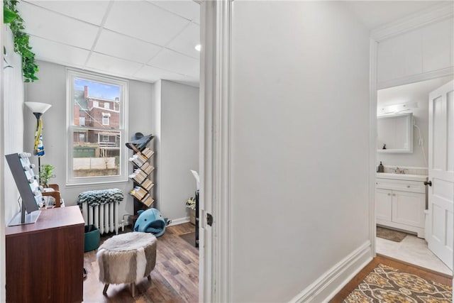 interior space with radiator heating unit, a paneled ceiling, baseboards, and wood finished floors