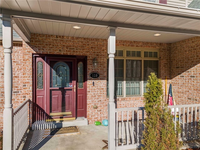 entrance to property with brick siding and a porch