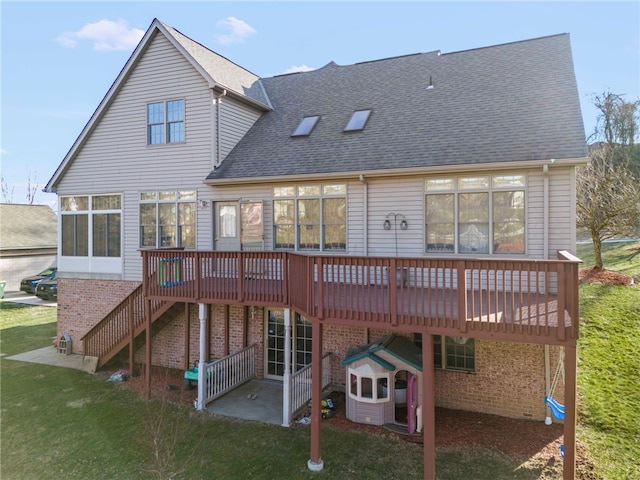 rear view of house featuring a lawn, stairway, a shingled roof, a wooden deck, and brick siding