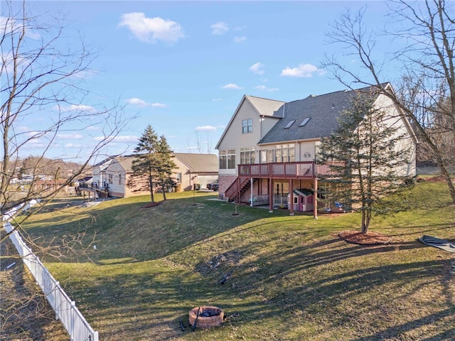 back of house featuring a fire pit, fence, stairway, a wooden deck, and a lawn