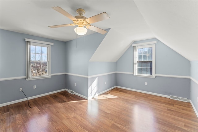 additional living space featuring vaulted ceiling, visible vents, baseboards, and wood finished floors