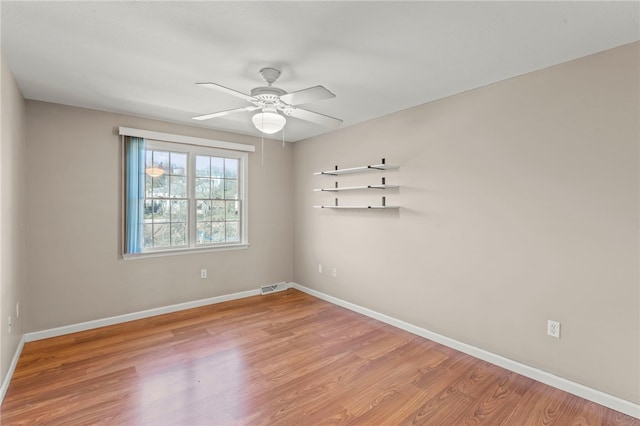 unfurnished room with visible vents, baseboards, wood finished floors, and a ceiling fan