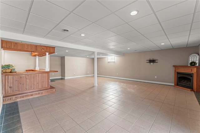 below grade area with light tile patterned floors, a drop ceiling, a fireplace, and baseboards