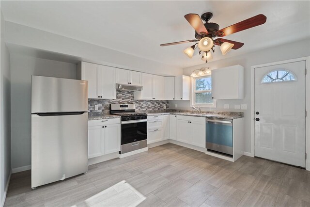 kitchen with tasteful backsplash, white cabinets, appliances with stainless steel finishes, and under cabinet range hood