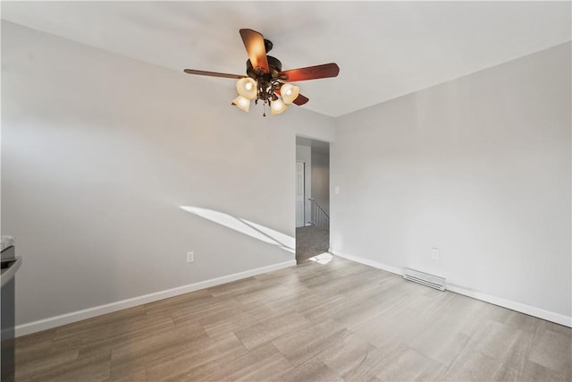 spare room featuring wood finished floors, visible vents, baseboards, and ceiling fan