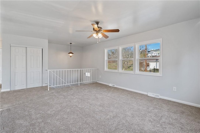 unfurnished room featuring visible vents, carpet, and a ceiling fan