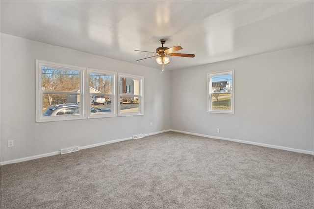 empty room featuring carpet, visible vents, and ceiling fan