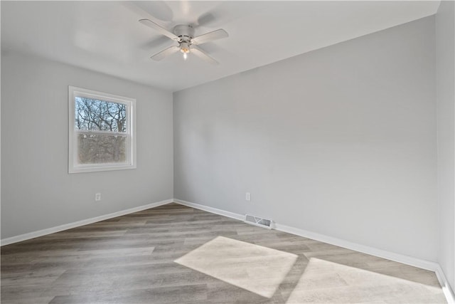 unfurnished room featuring wood finished floors, visible vents, baseboards, and ceiling fan