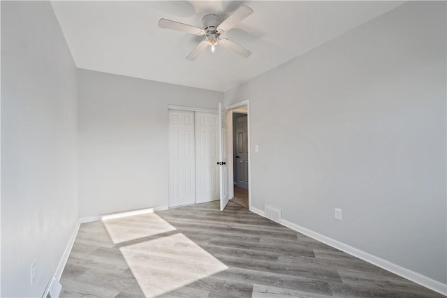 spare room with wood finished floors, visible vents, baseboards, and ceiling fan