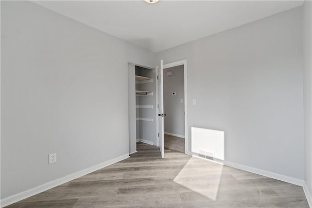 unfurnished room featuring visible vents, baseboards, and wood finished floors