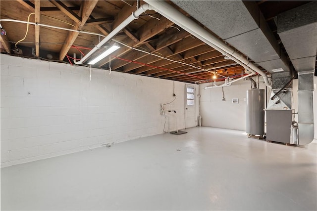 basement featuring concrete block wall, heating unit, and water heater